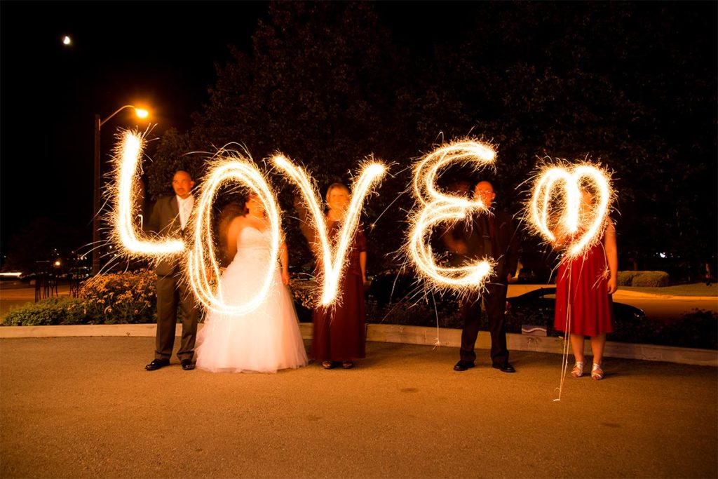 open house at Carmen's demonstrating a wedding party spelling LOVE with sparklers outdoors at night